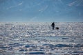 male hiker with backpack walking on ice water surface against peaks on shore,russia, lake